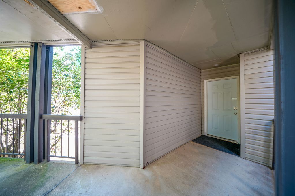 A large empty room with a balcony and a door.