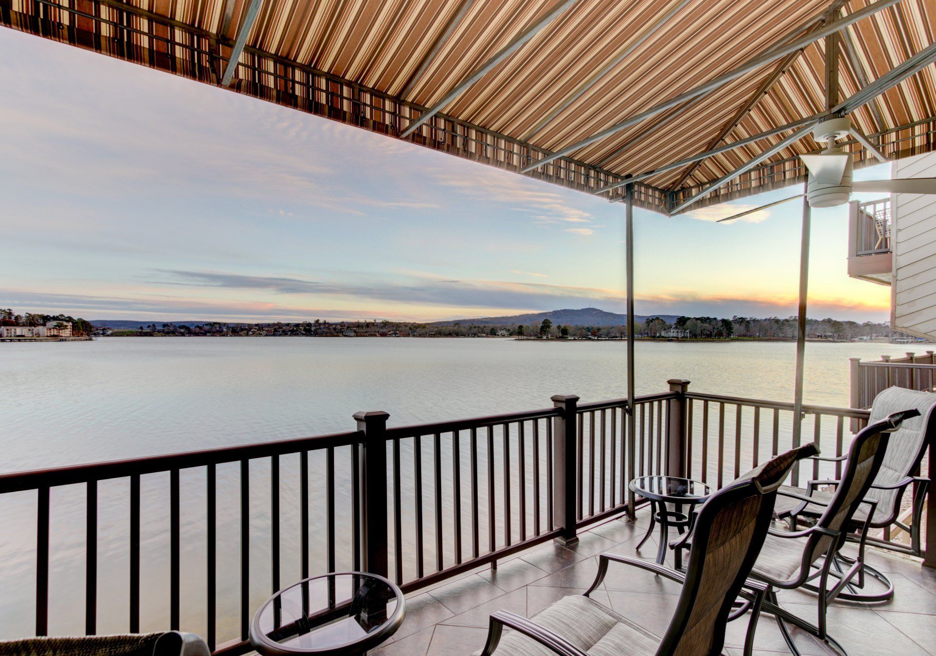 A balcony with chairs and a table overlooking a body of water.