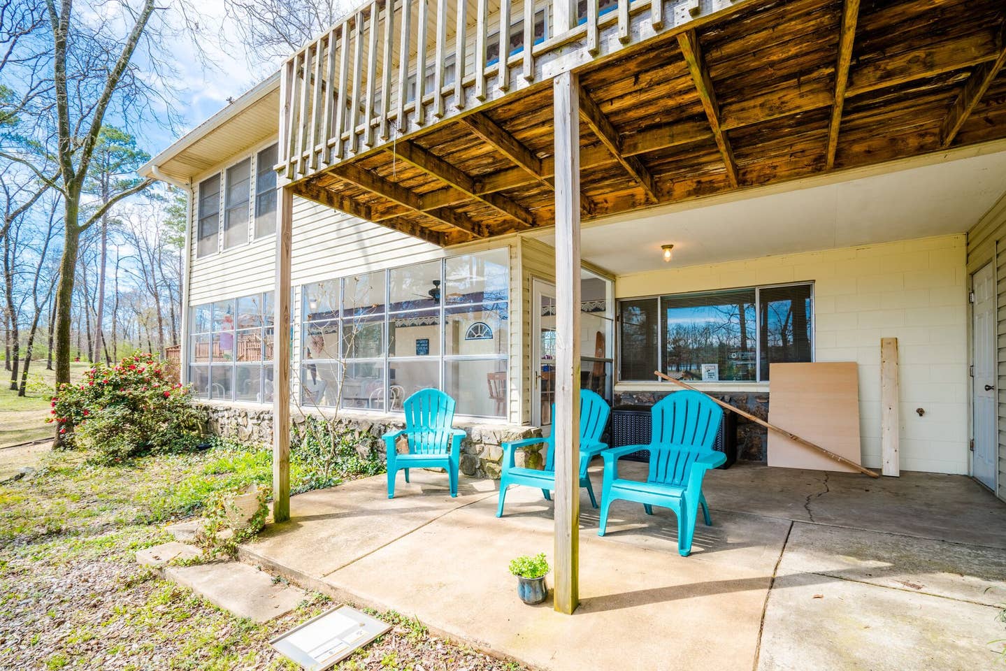 A patio with blue chairs and a table under a wooden pergola.