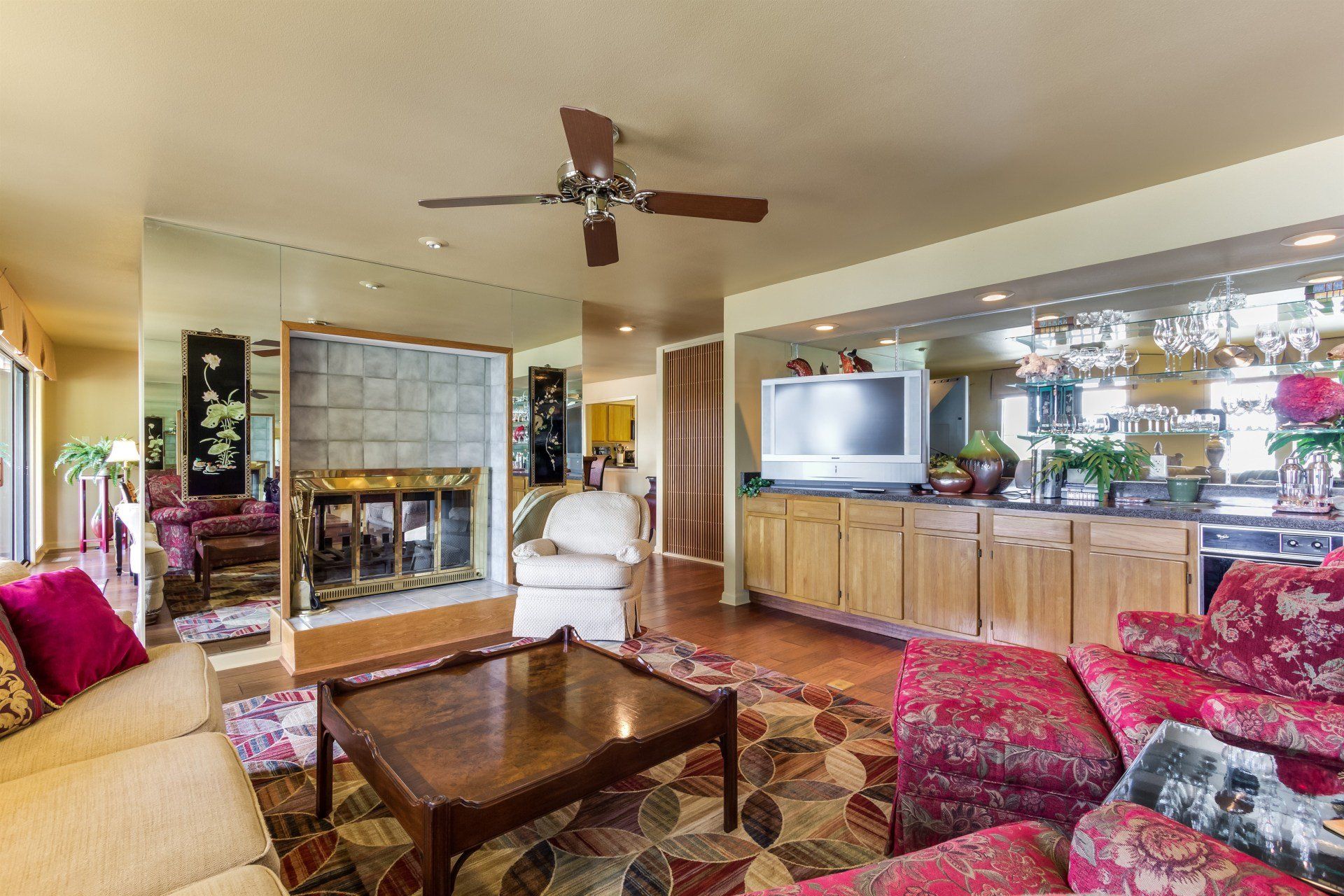 A living room with a couch , chairs , coffee table , television and fireplace.