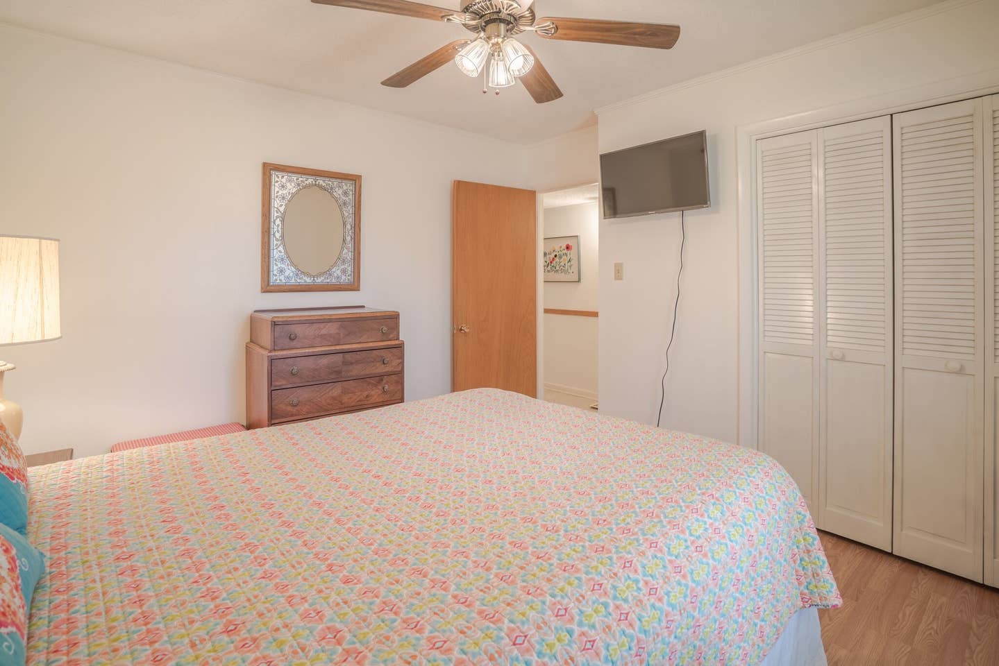 A bedroom with a bed , dresser , television and ceiling fan.