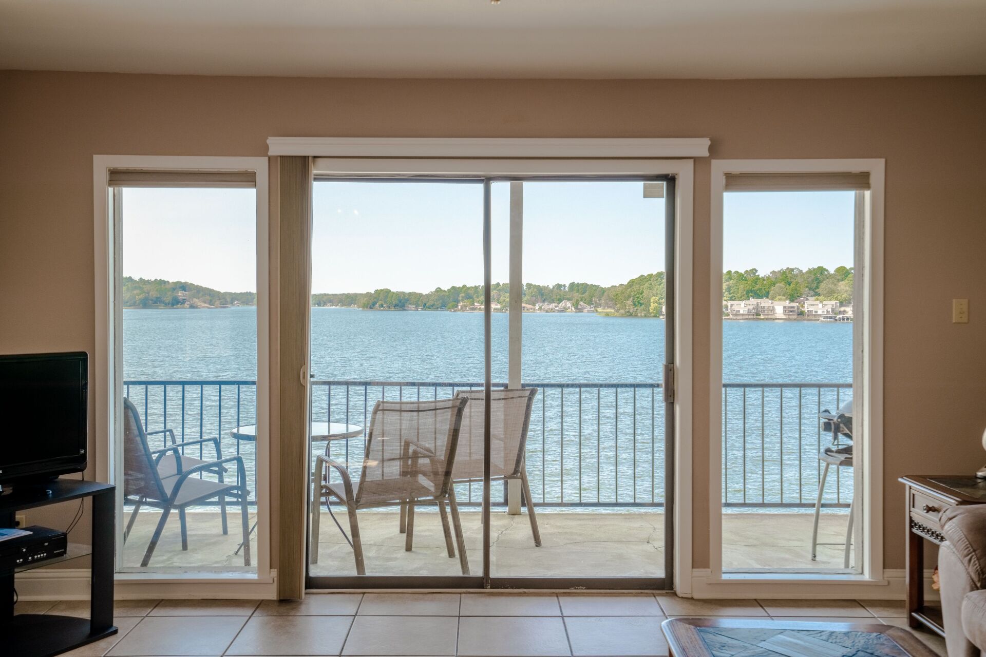 A living room with sliding glass doors leading to a balcony overlooking a lake.