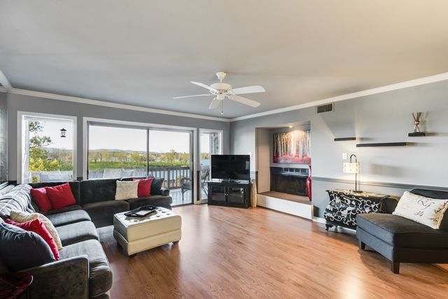 A living room with a couch , chair , table , television and ceiling fan.