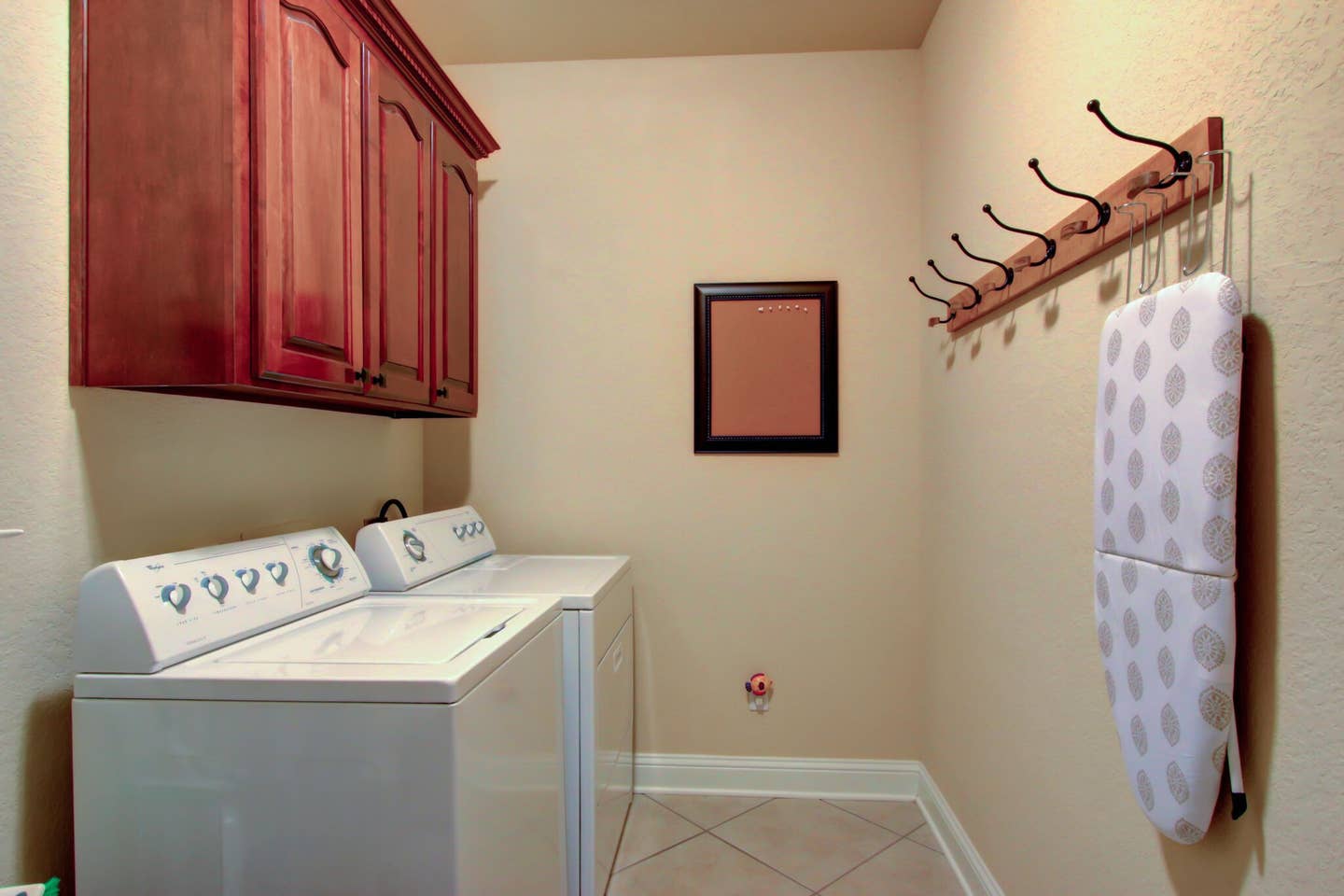 A laundry room with a washer and dryer and an ironing board.