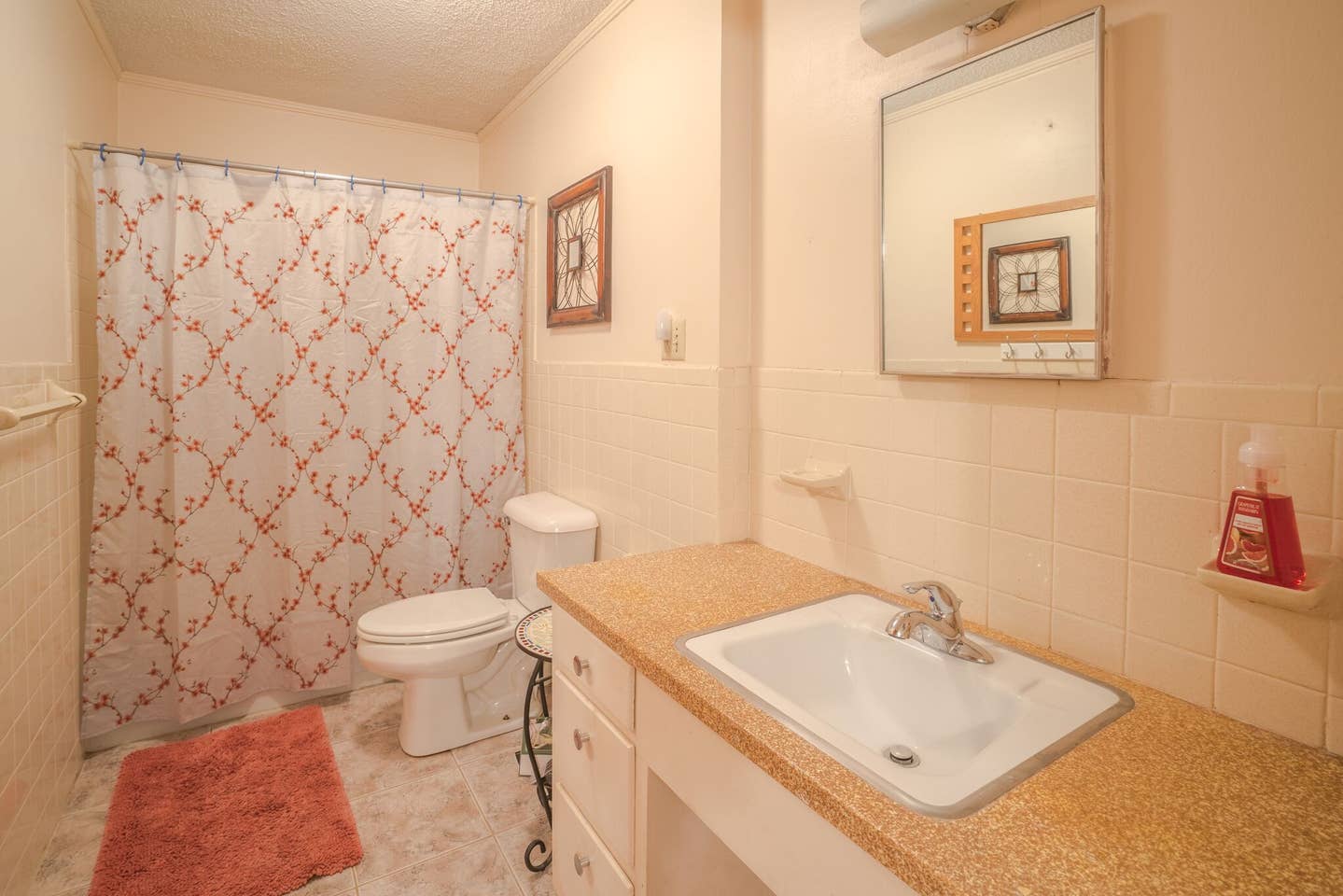 A bathroom with a toilet , sink , mirror and shower curtain.