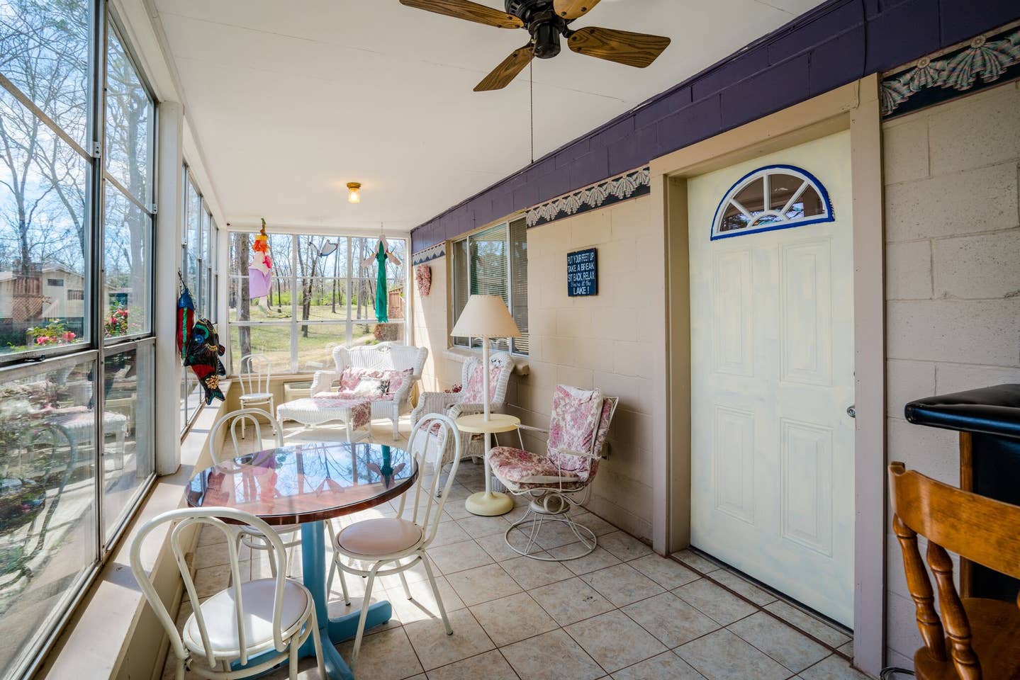 A sun room with a table and chairs and a ceiling fan.