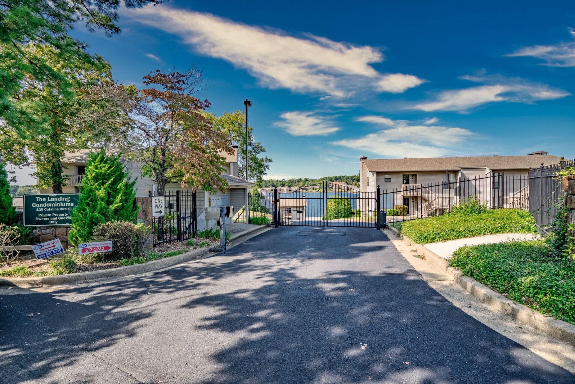 A gated entrance to a residential area with a fence and trees.
