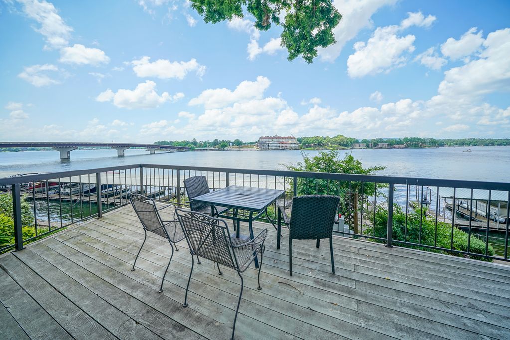 A wooden deck with a table and chairs overlooking a river.