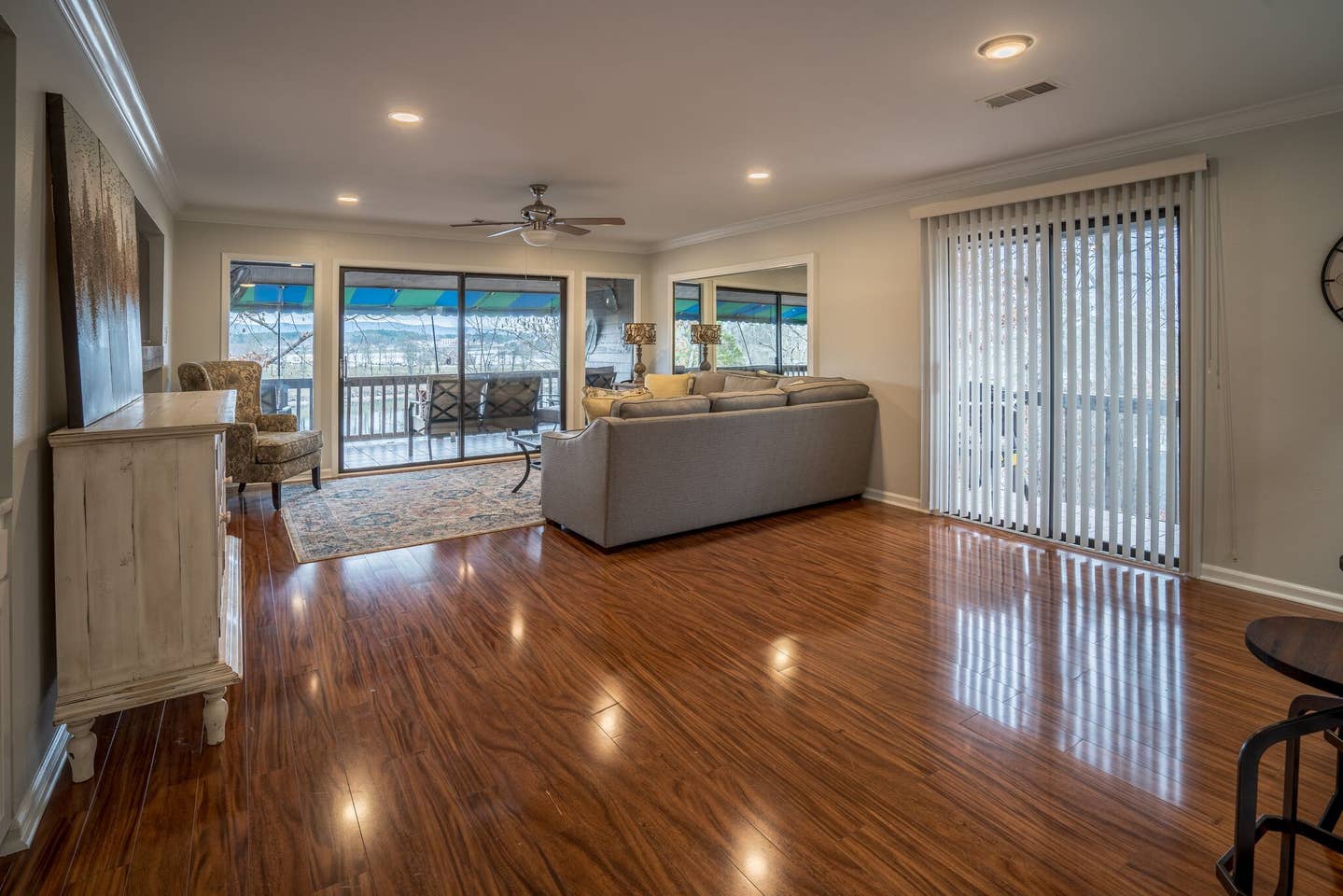 A living room with hardwood floors , a couch , chairs and sliding glass doors.