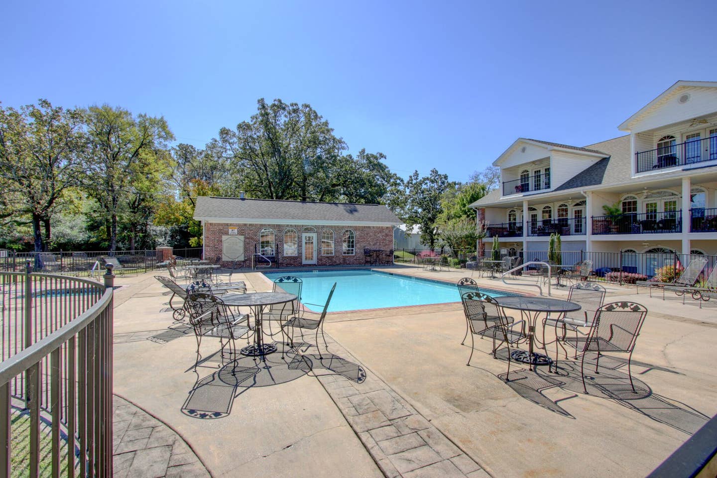 A large swimming pool with tables and chairs around it