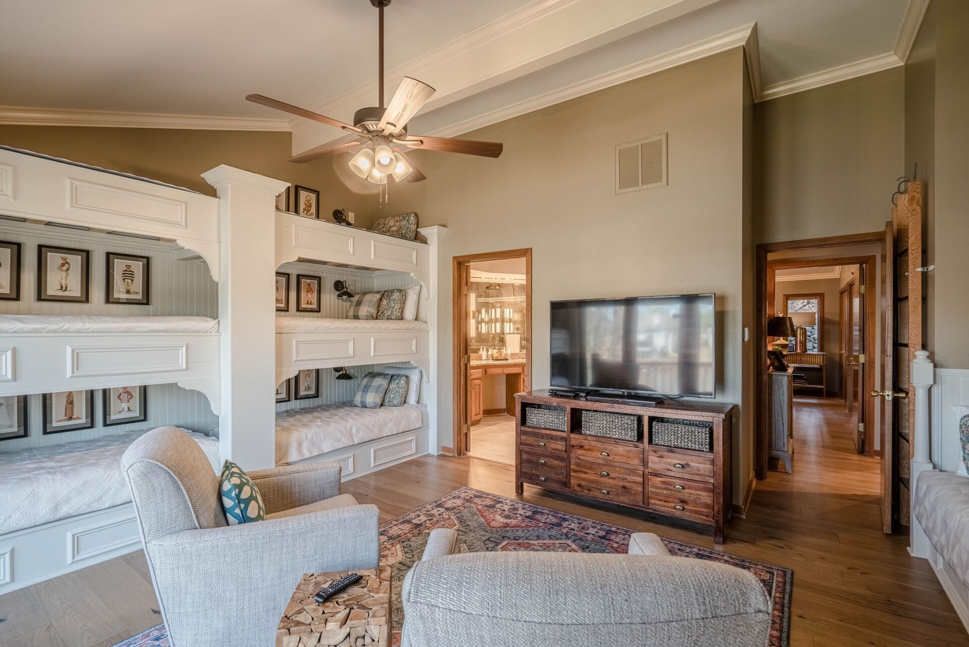 A living room with bunk beds , chairs , a television and a ceiling fan.
