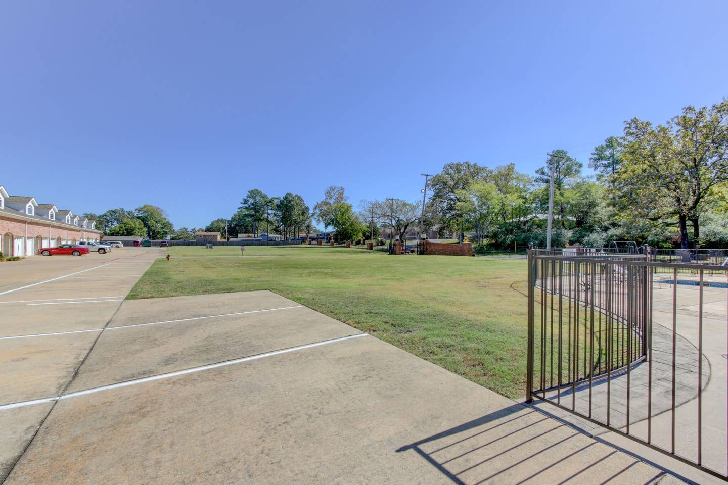 A fence surrounds a large grassy field in front of a building.