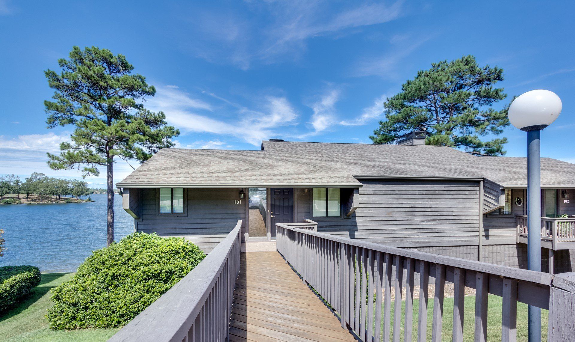 A wooden walkway leading to a house with a lake in the background
