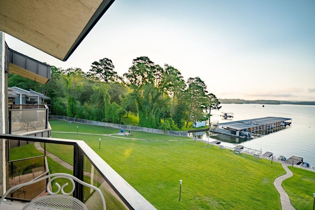 A view of a lake from a balcony with a table and chairs.