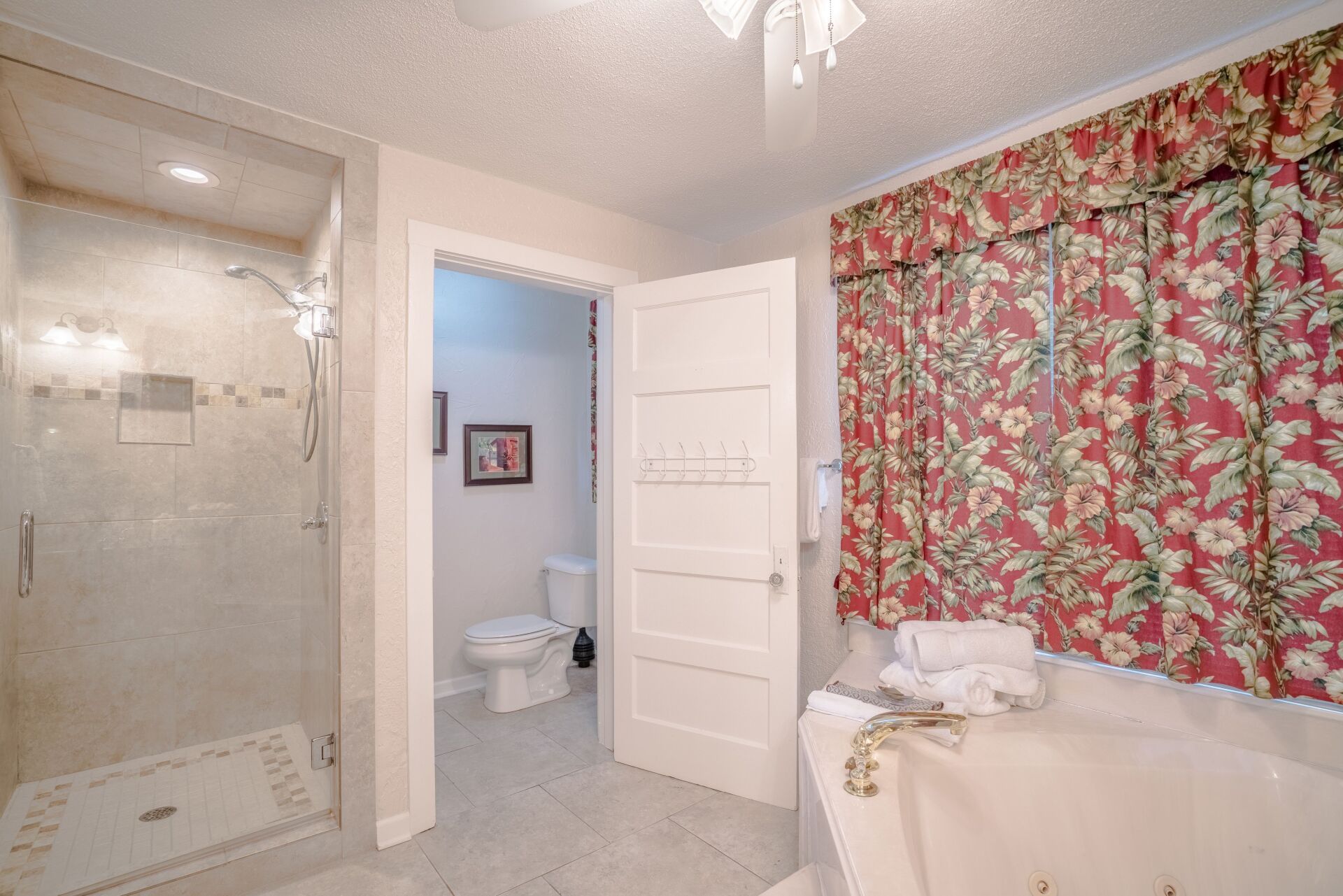A bathroom with a tub , toilet , shower and window.