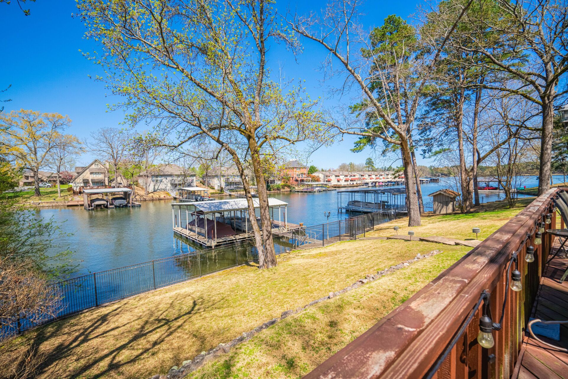A wooden deck overlooking a lake with boats docked on the shore.
