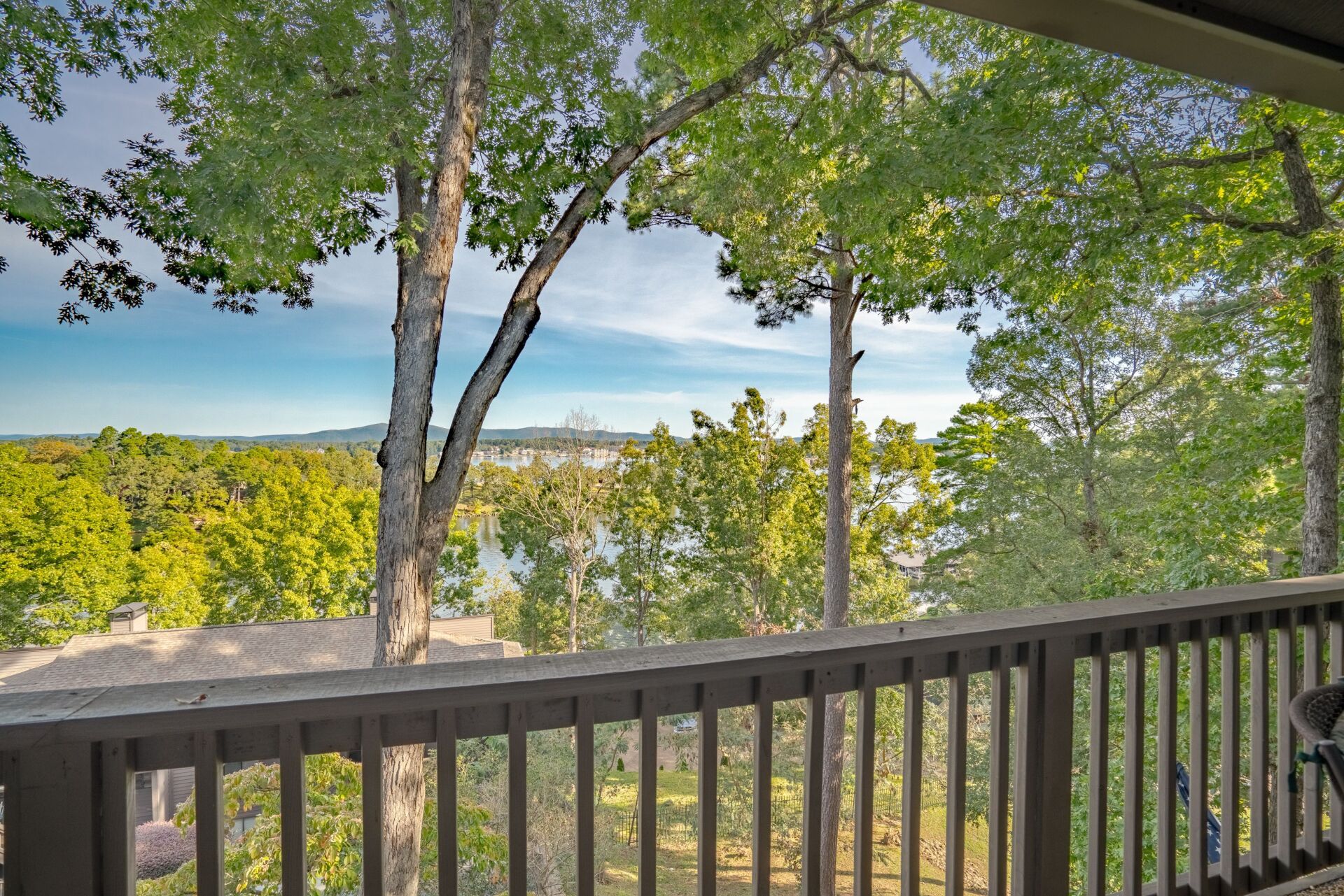 A balcony with a view of a lake and trees.