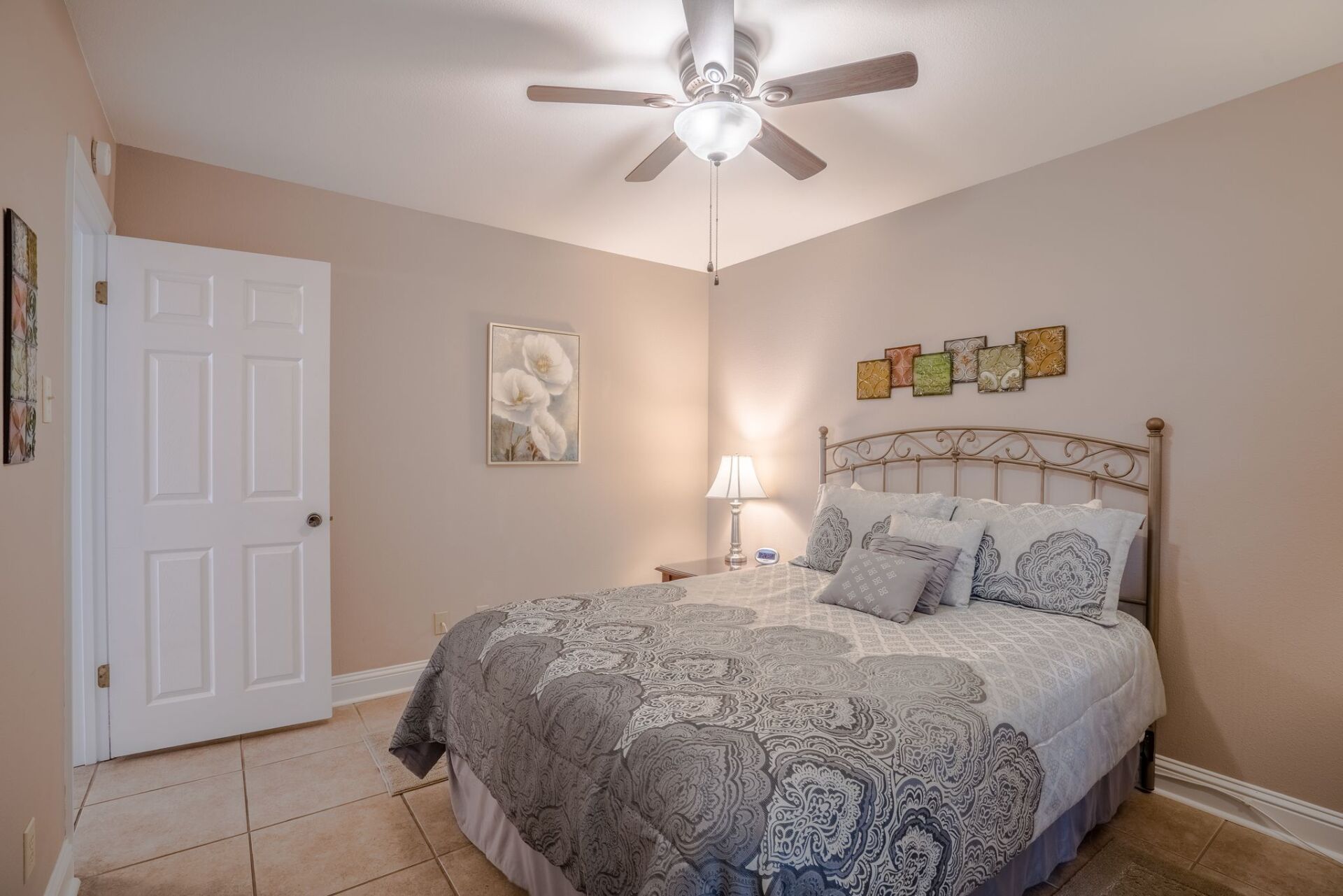 A bedroom with a king size bed and a ceiling fan.