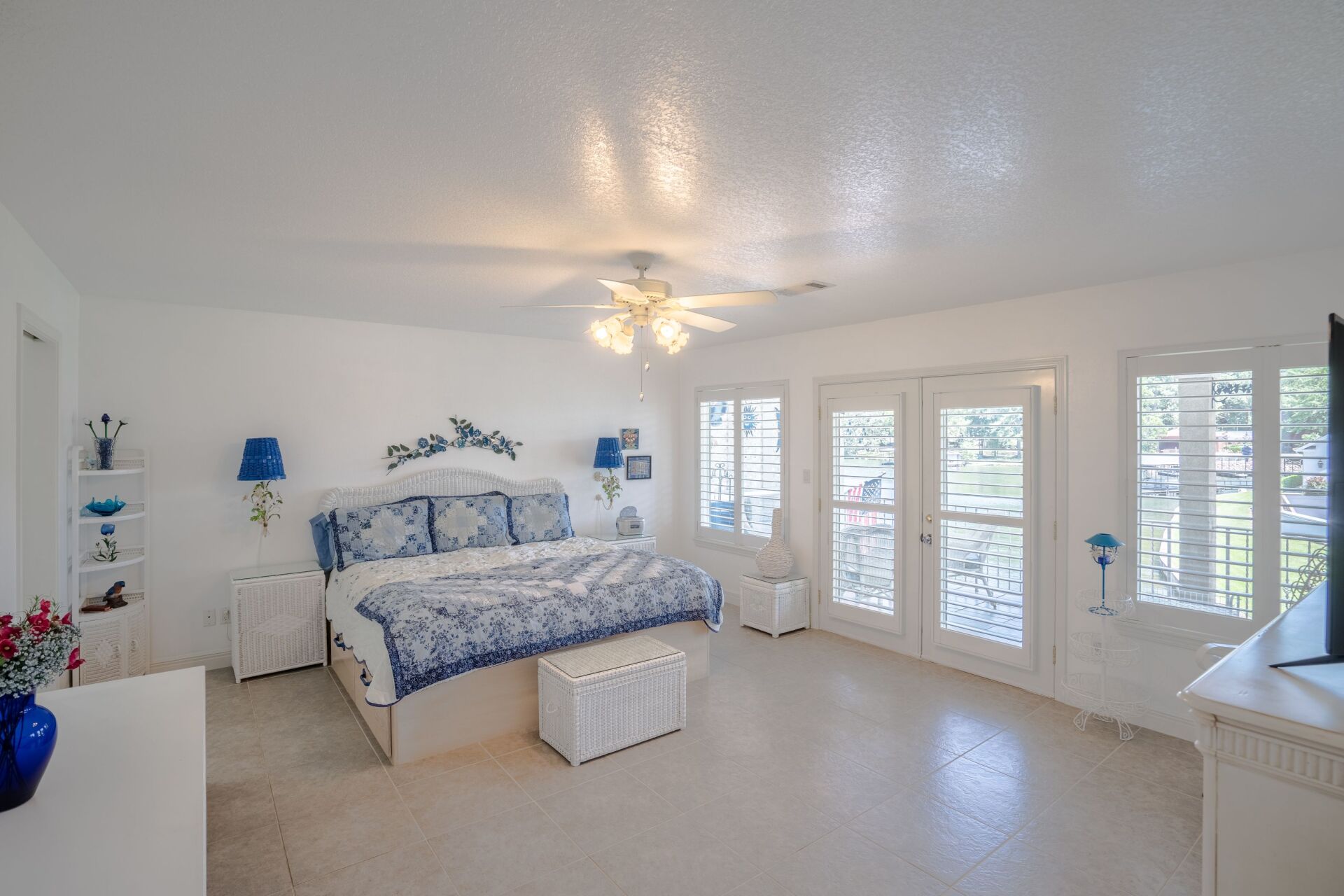 A bedroom with a king size bed , a ceiling fan , a dresser and a television.