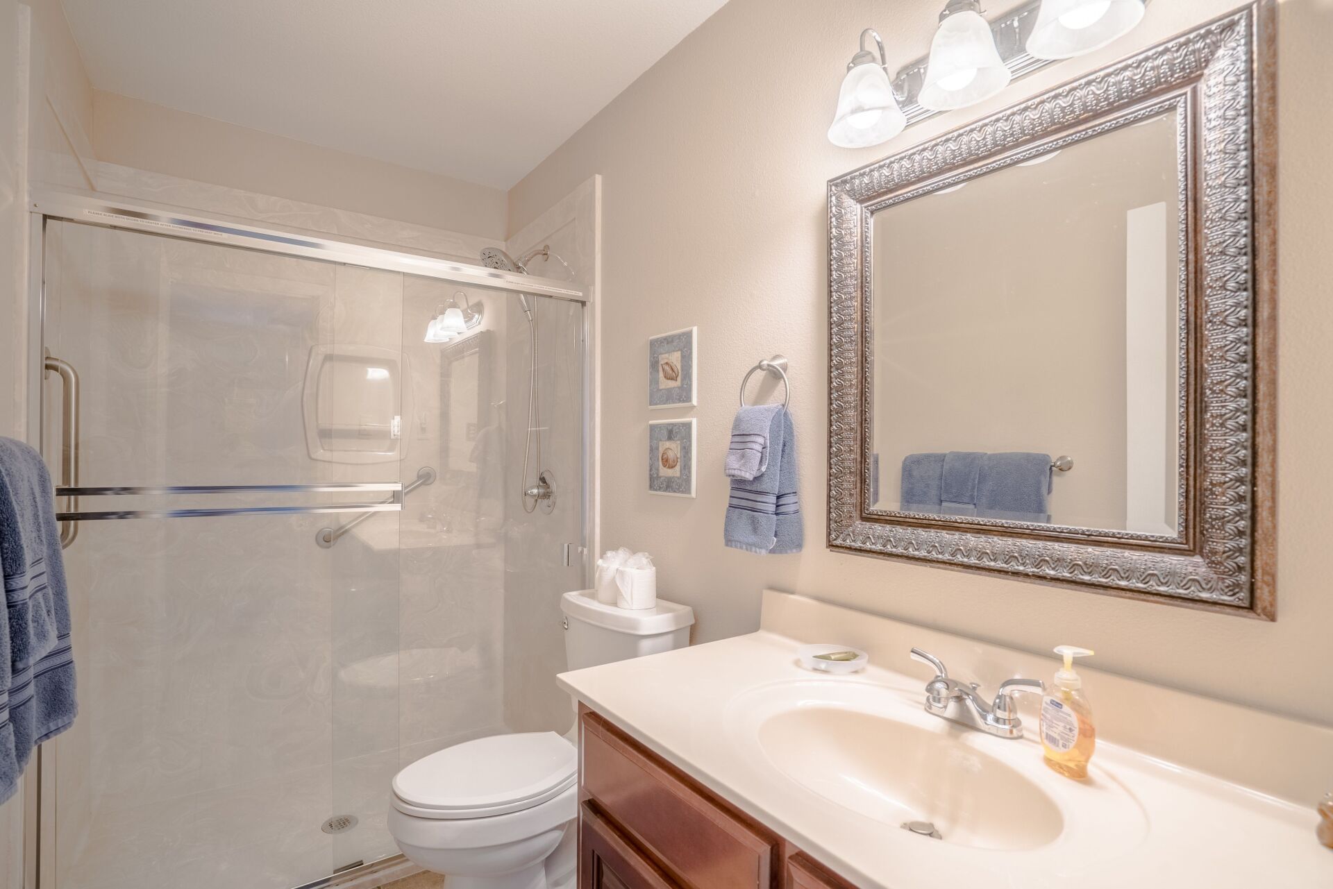 A bathroom with a toilet , sink , mirror and shower.