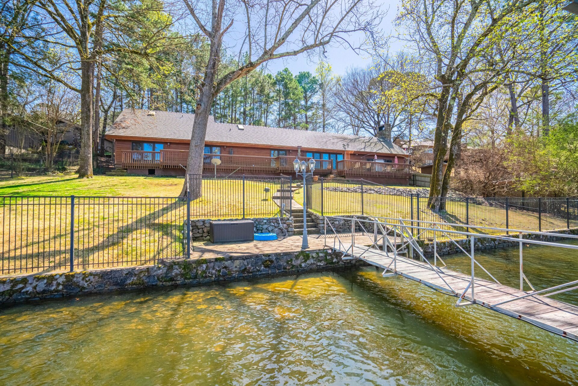 A house is sitting on the shore of a lake next to a dock.