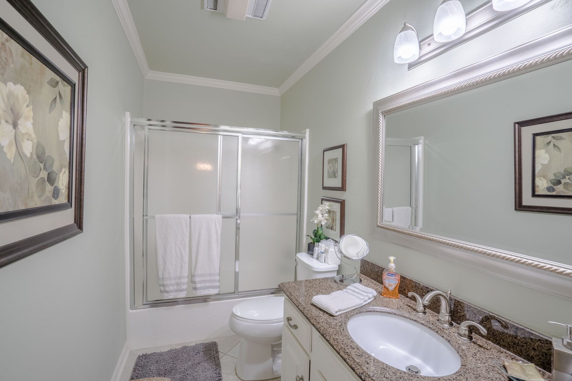 A bathroom with a toilet , sink , mirror and shower stall.