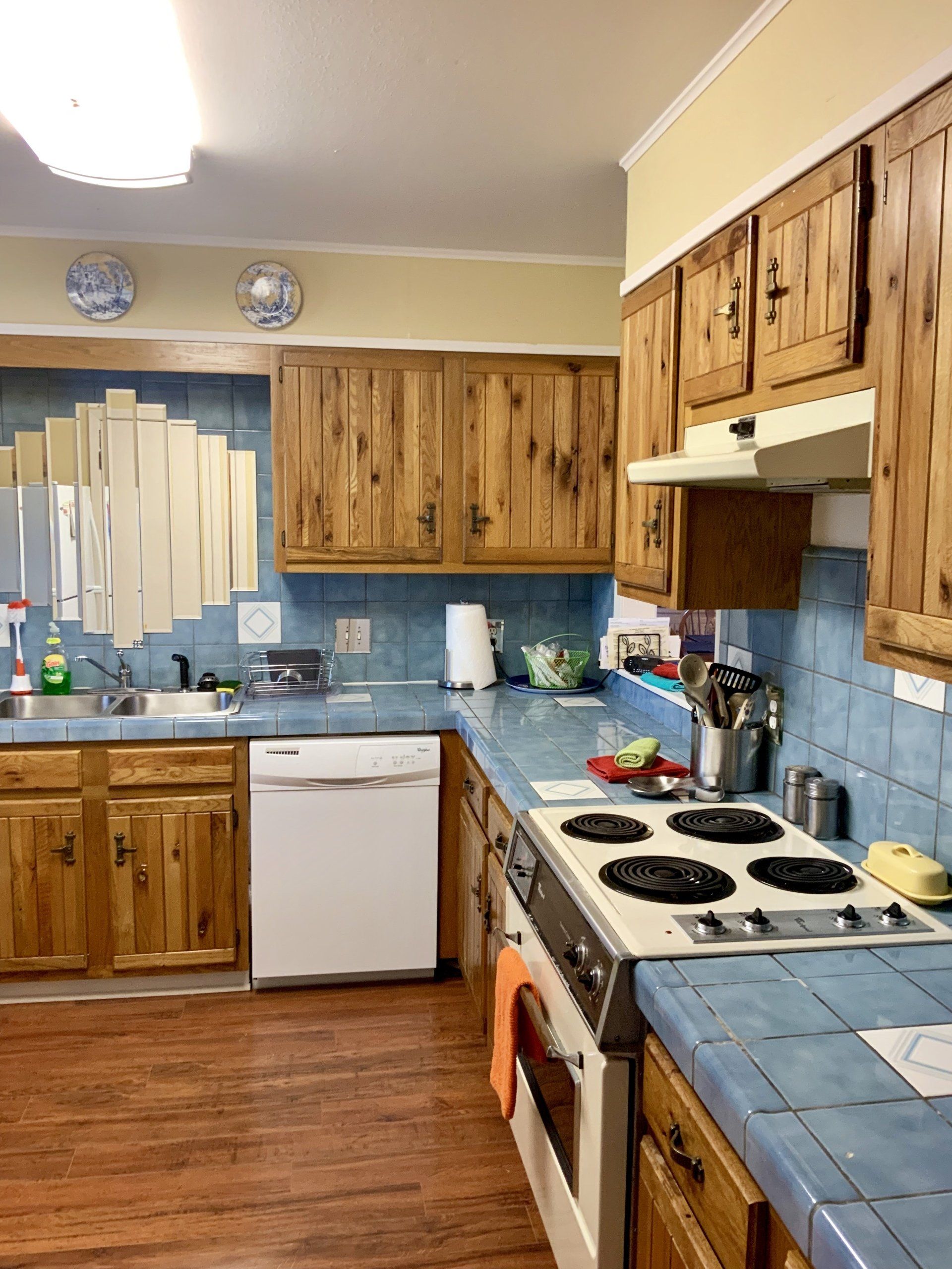 A kitchen with wooden cabinets , a stove , a dishwasher , and a sink.
