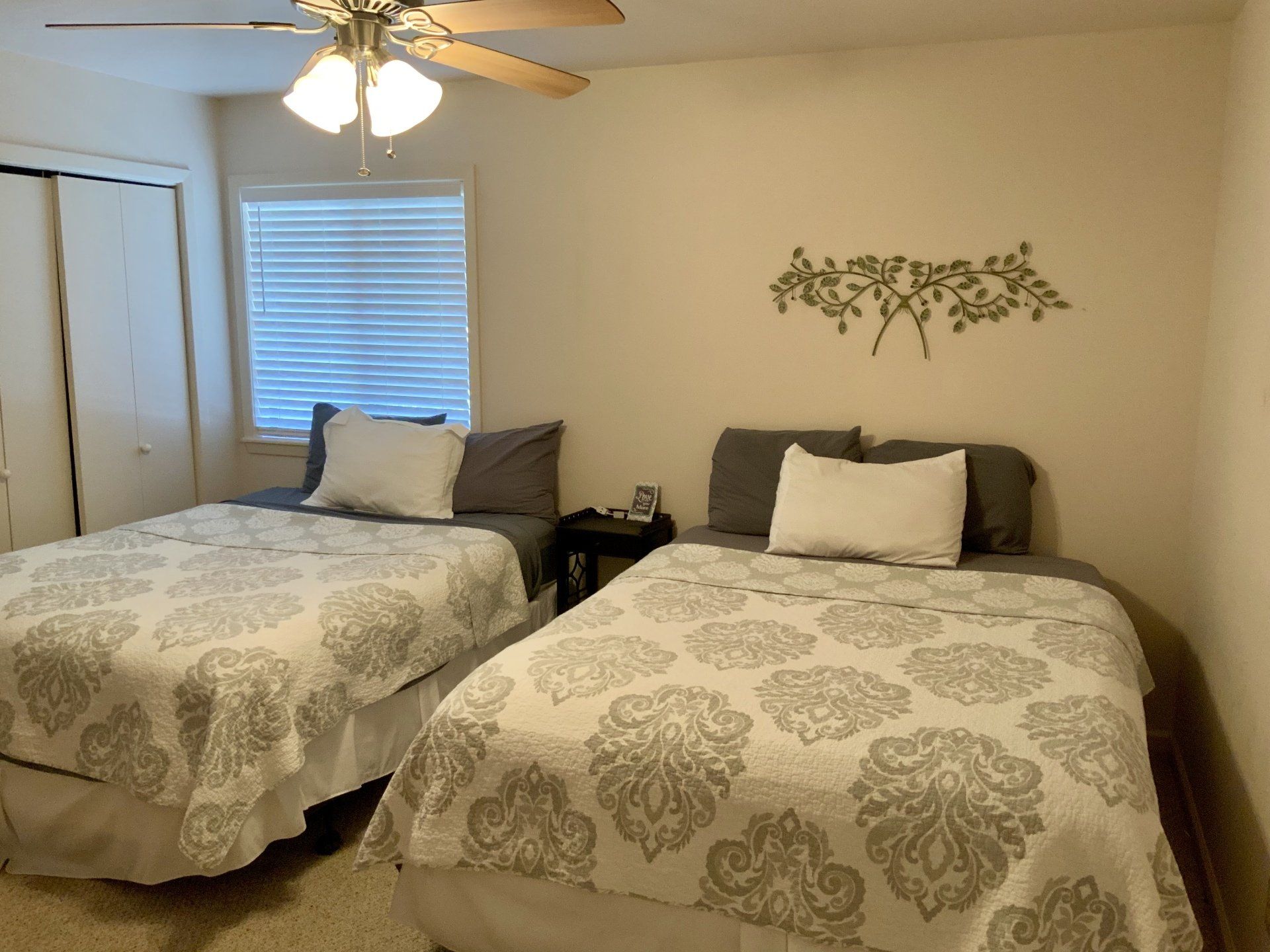 A bedroom with two beds and a ceiling fan.
