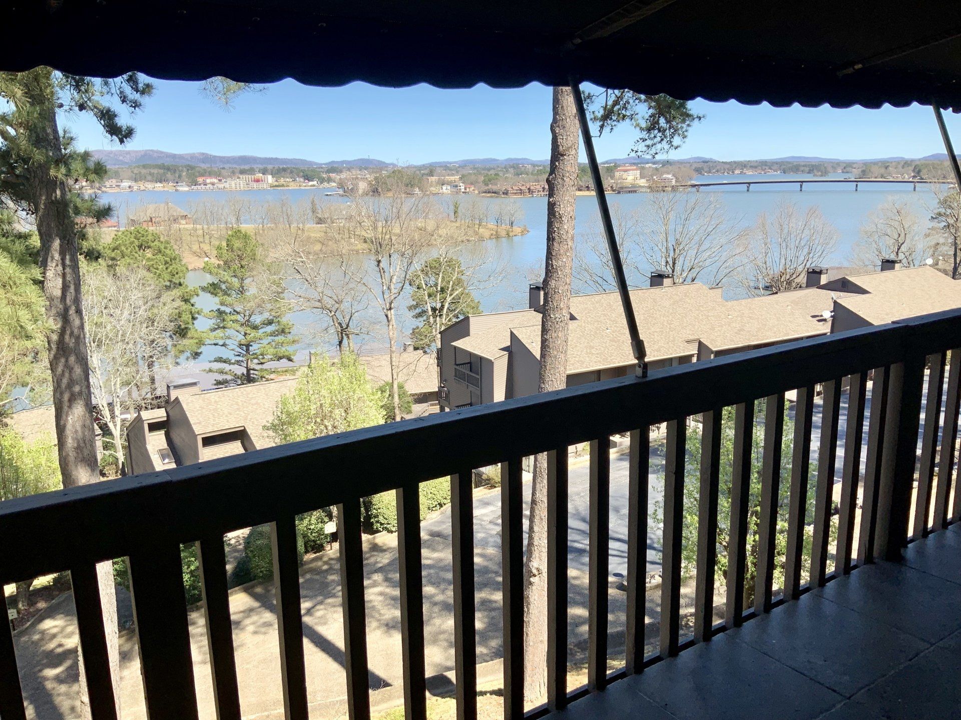 A balcony with a view of a lake and trees.