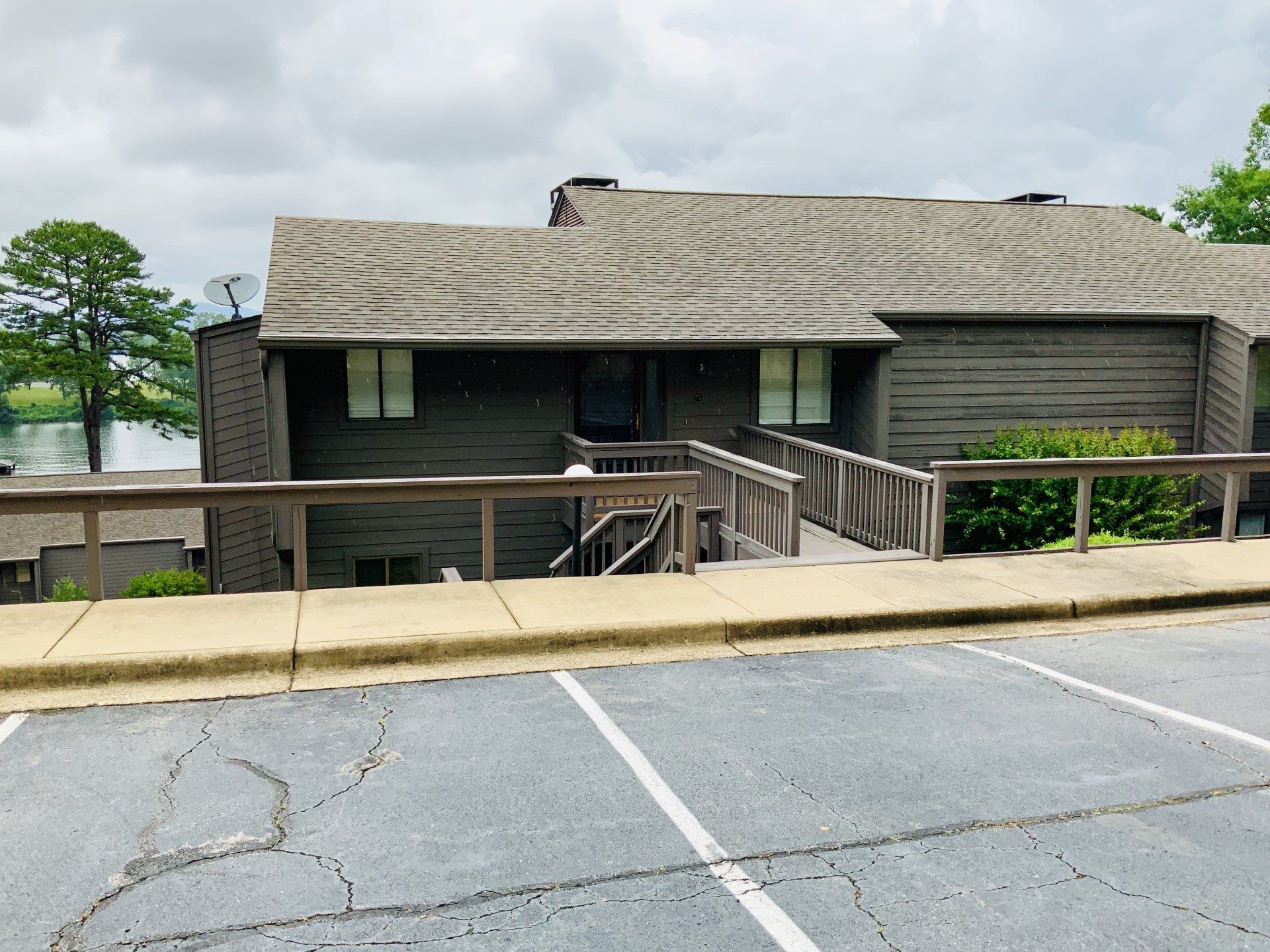 A large house with stairs leading up to it is next to a parking lot.