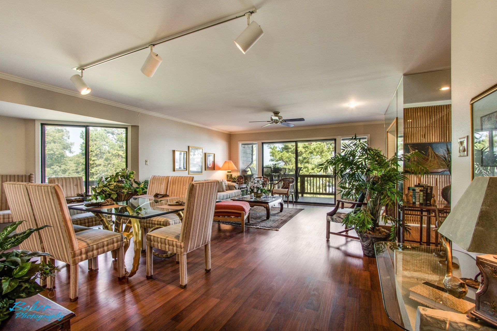 A living room with hardwood floors , a dining room table and chairs , and a ceiling fan.