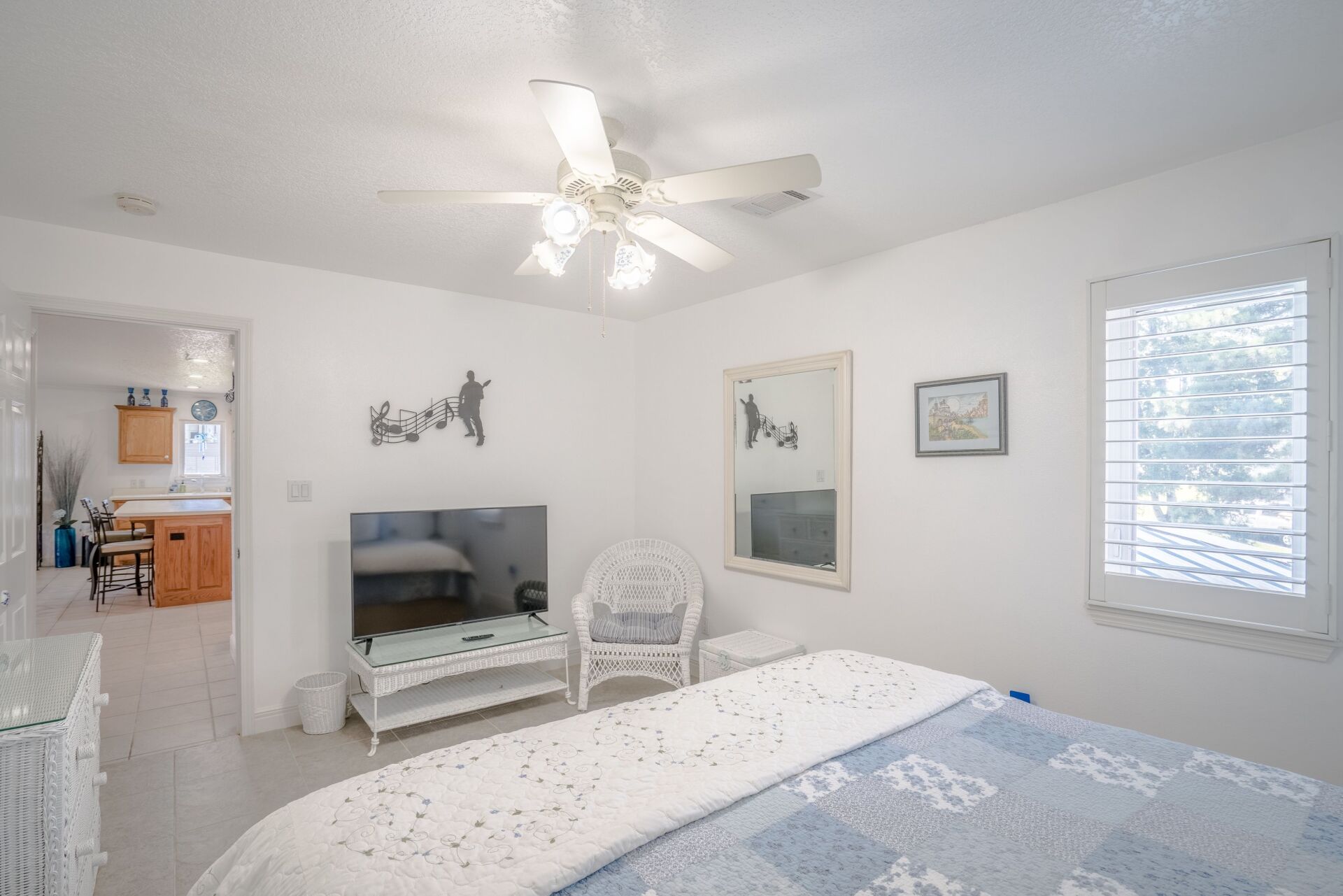 A bedroom with a bed , chair , television and ceiling fan.
