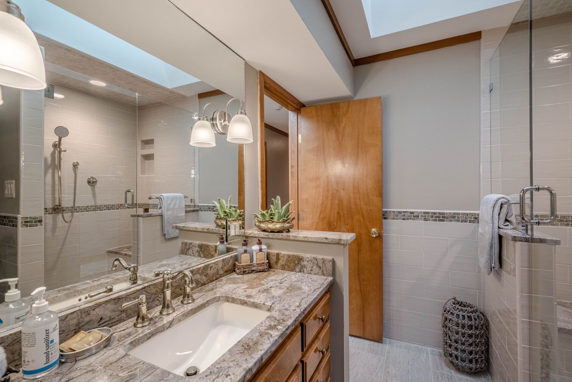 A bathroom with a sink , mirror and shower.