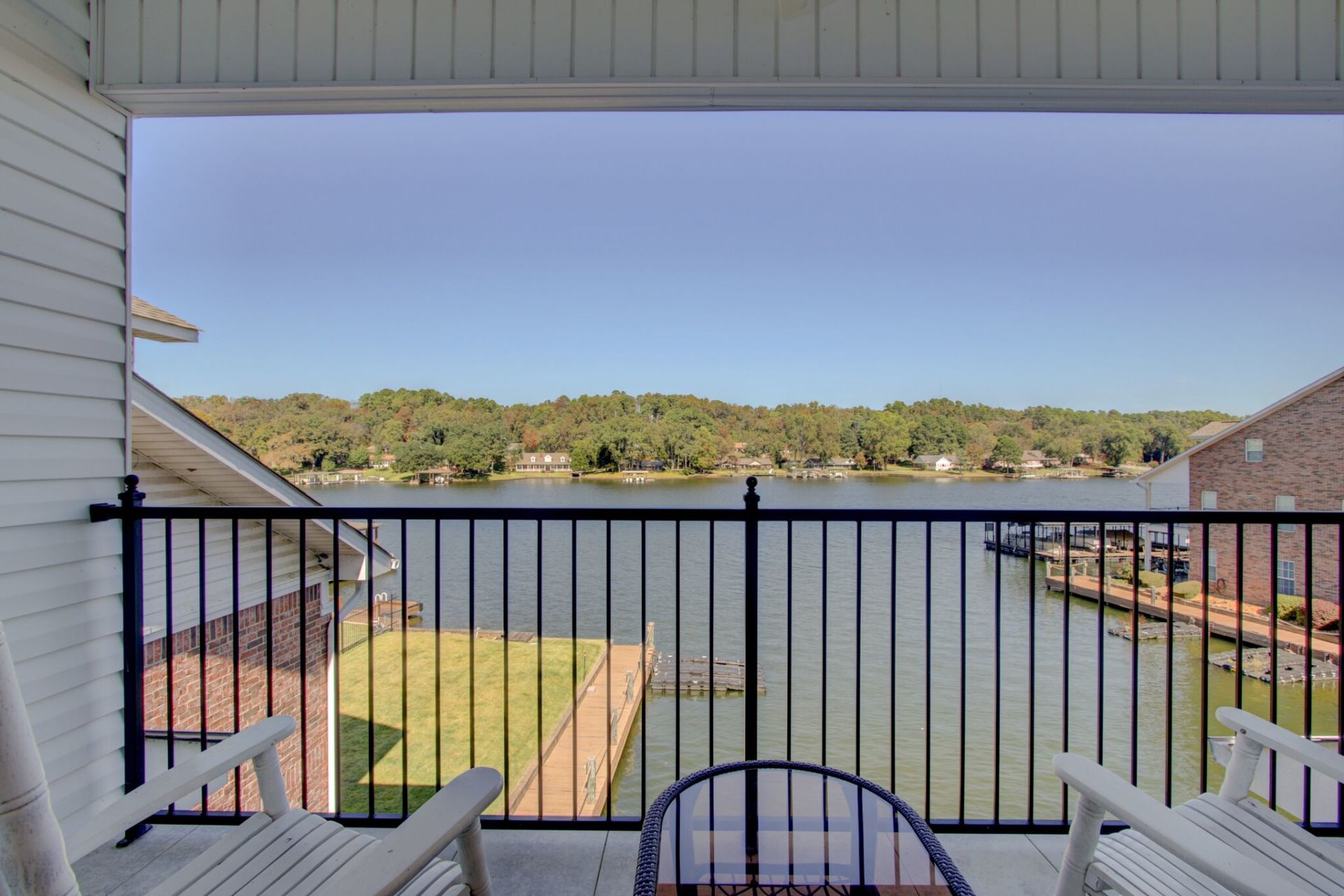 A balcony with chairs and a table overlooking a lake.
