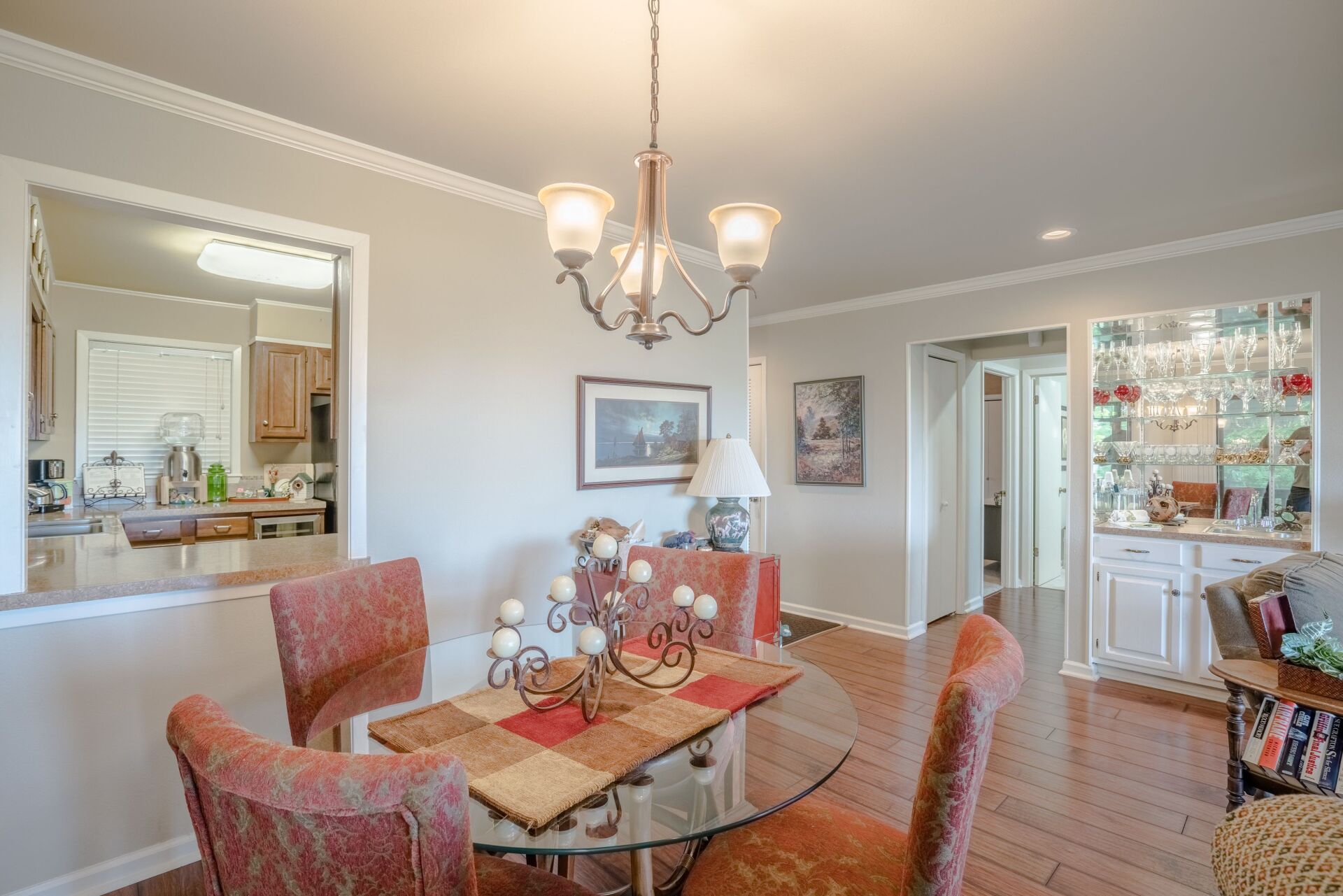A dining room with a glass table and chairs and a chandelier.