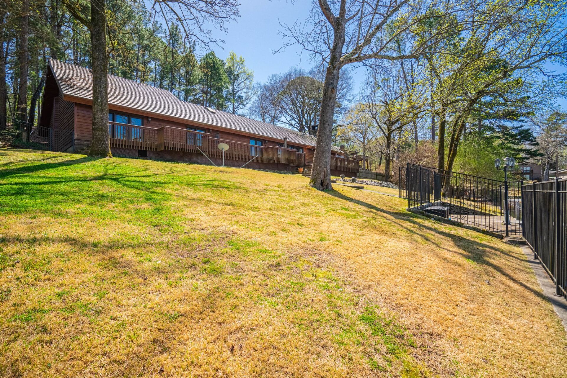 A large house is sitting on top of a lush green hill surrounded by trees.