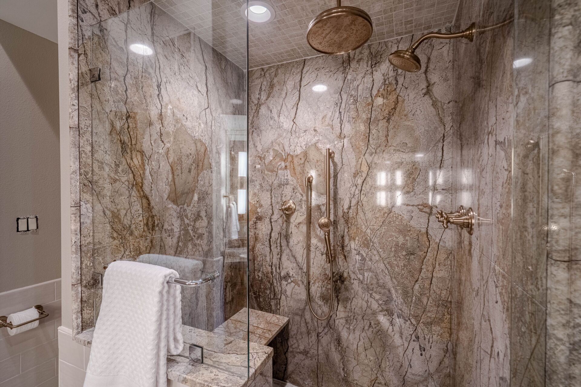A bathroom with a walk in shower and marble walls.