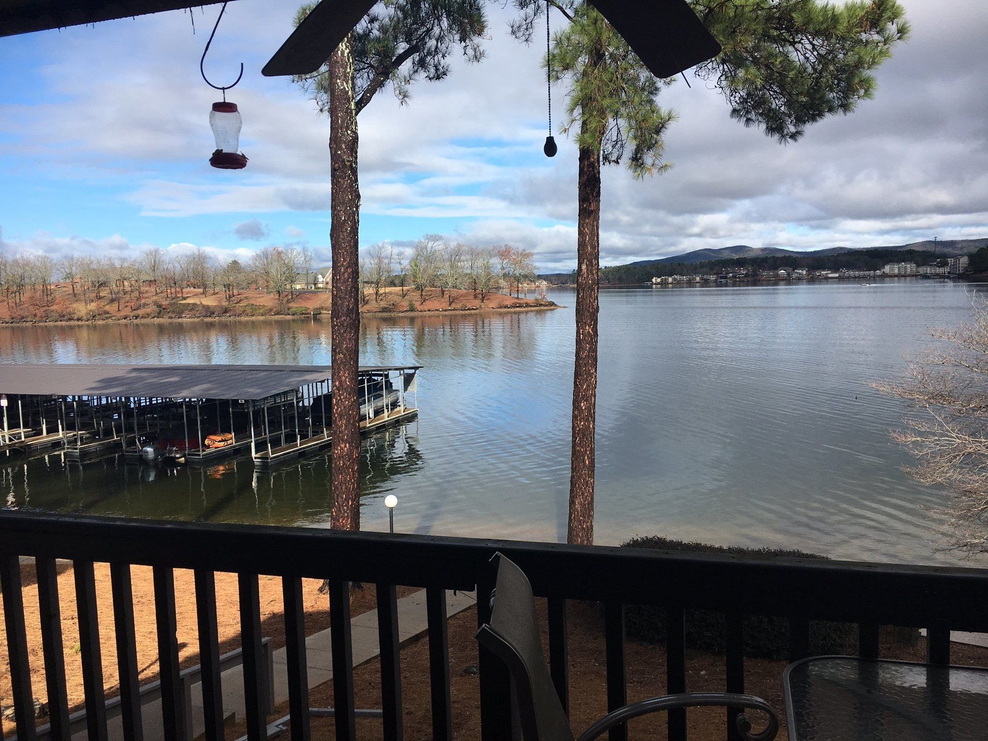 A view of a lake from a deck with a ceiling fan.