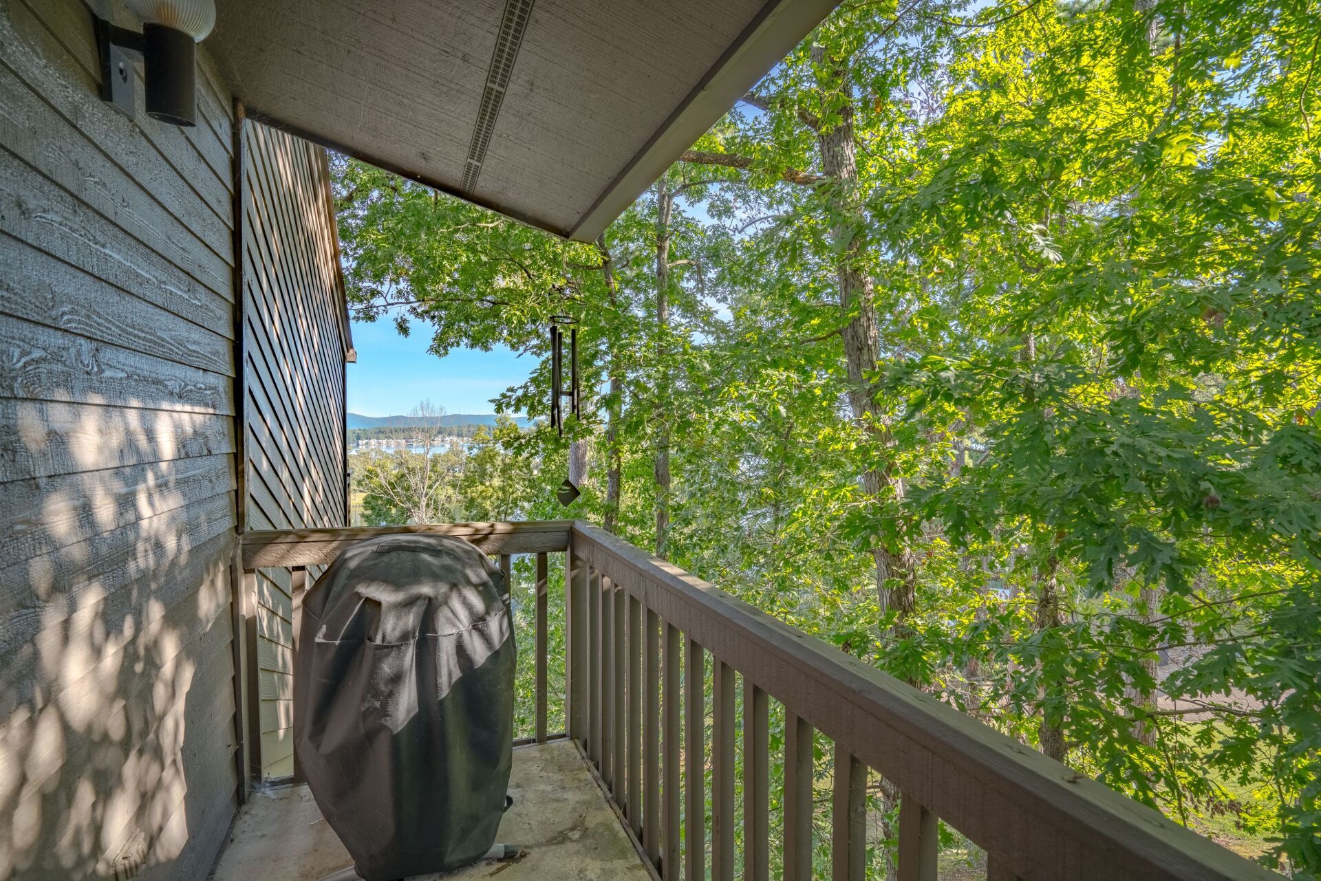 A balcony with a grill and trees in the background.