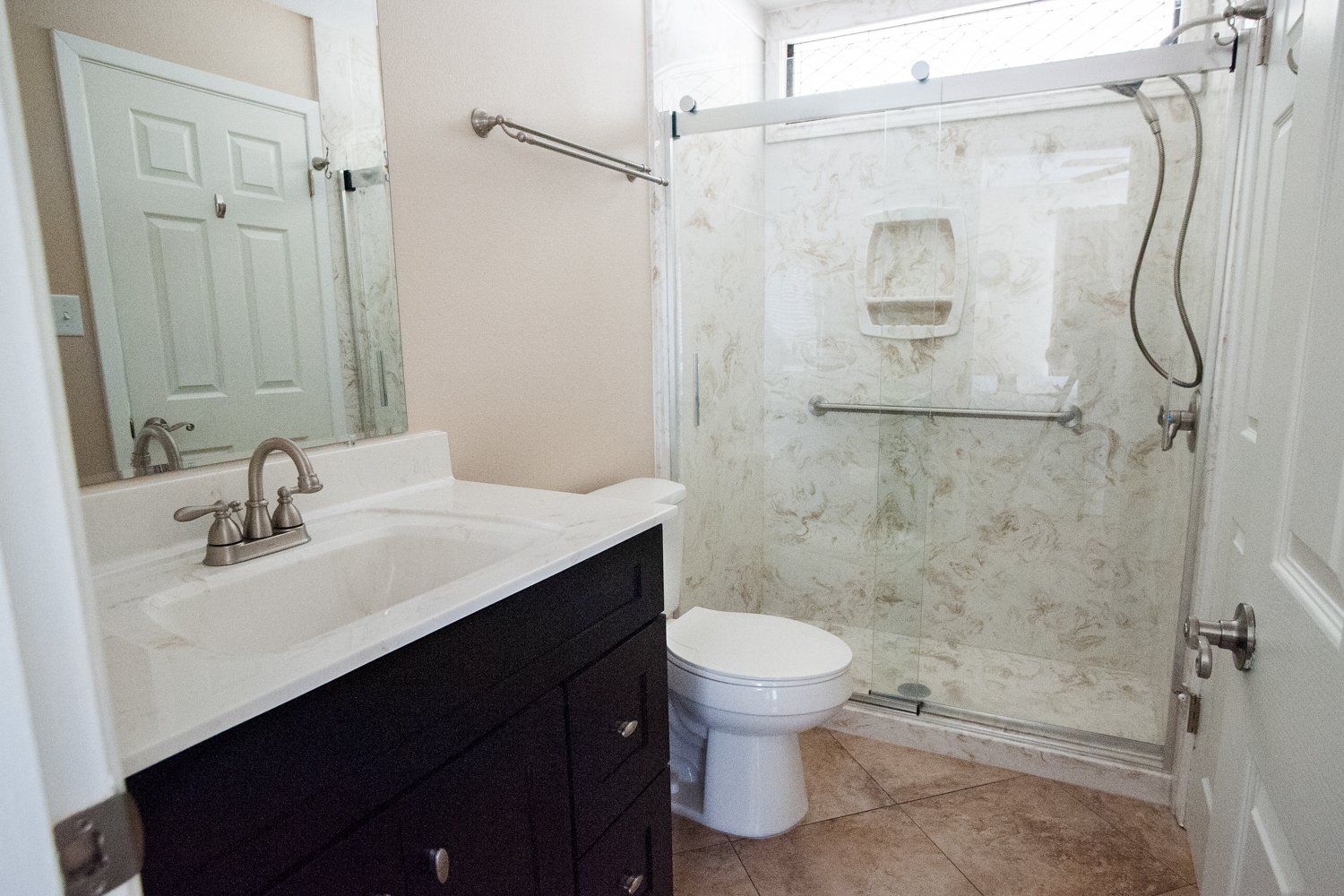 A bathroom with a toilet , sink and shower.