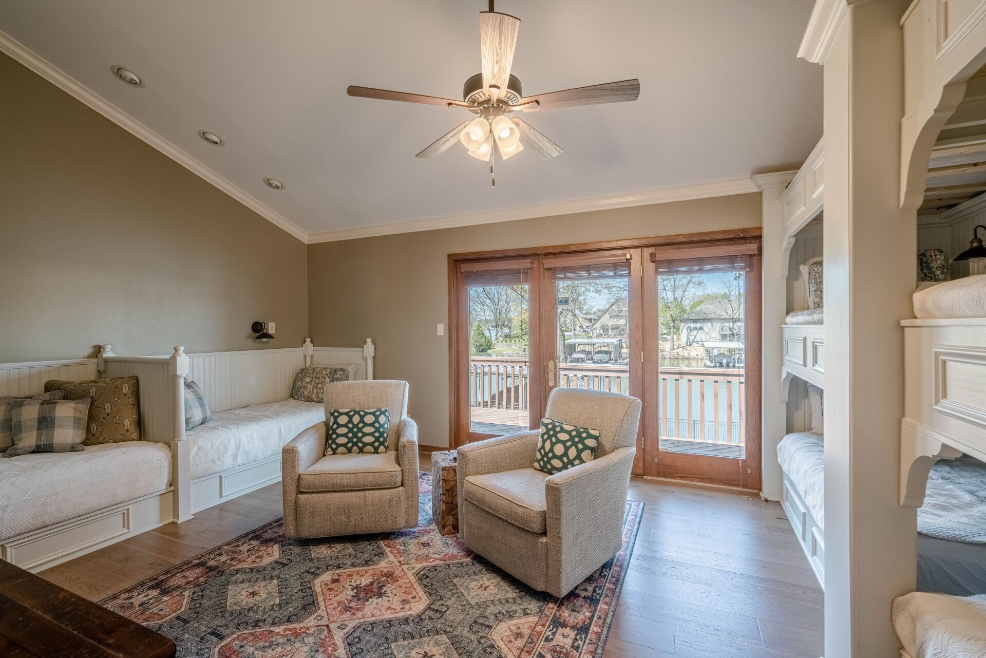 A living room with bunk beds , chairs , and a ceiling fan.