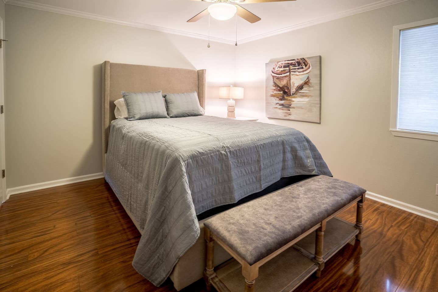 A bedroom with a bed , bench and ceiling fan.