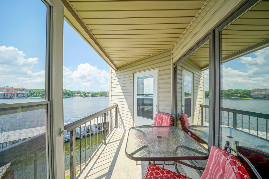 A balcony with a table and chairs overlooking a lake.
