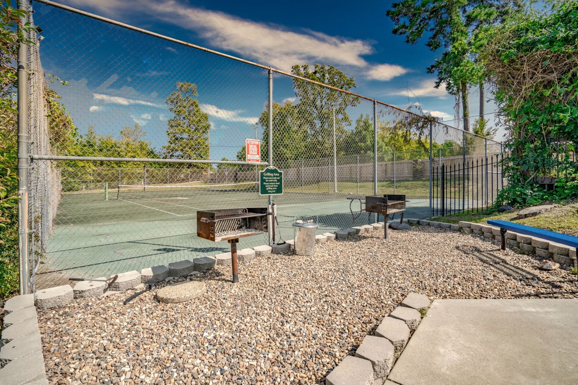 A tennis court with a fence surrounding it and trees in the background.