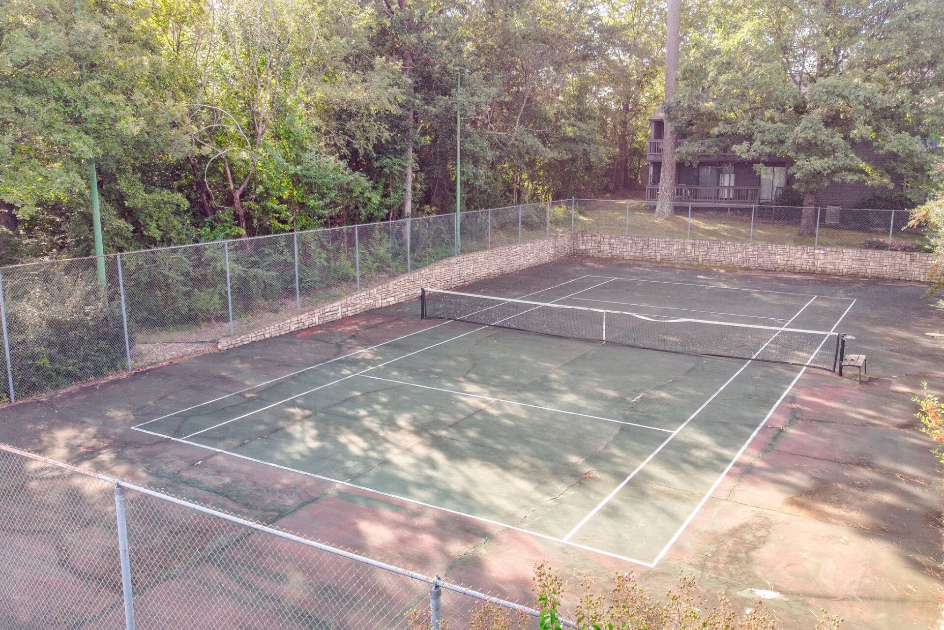 An aerial view of a tennis court surrounded by trees.