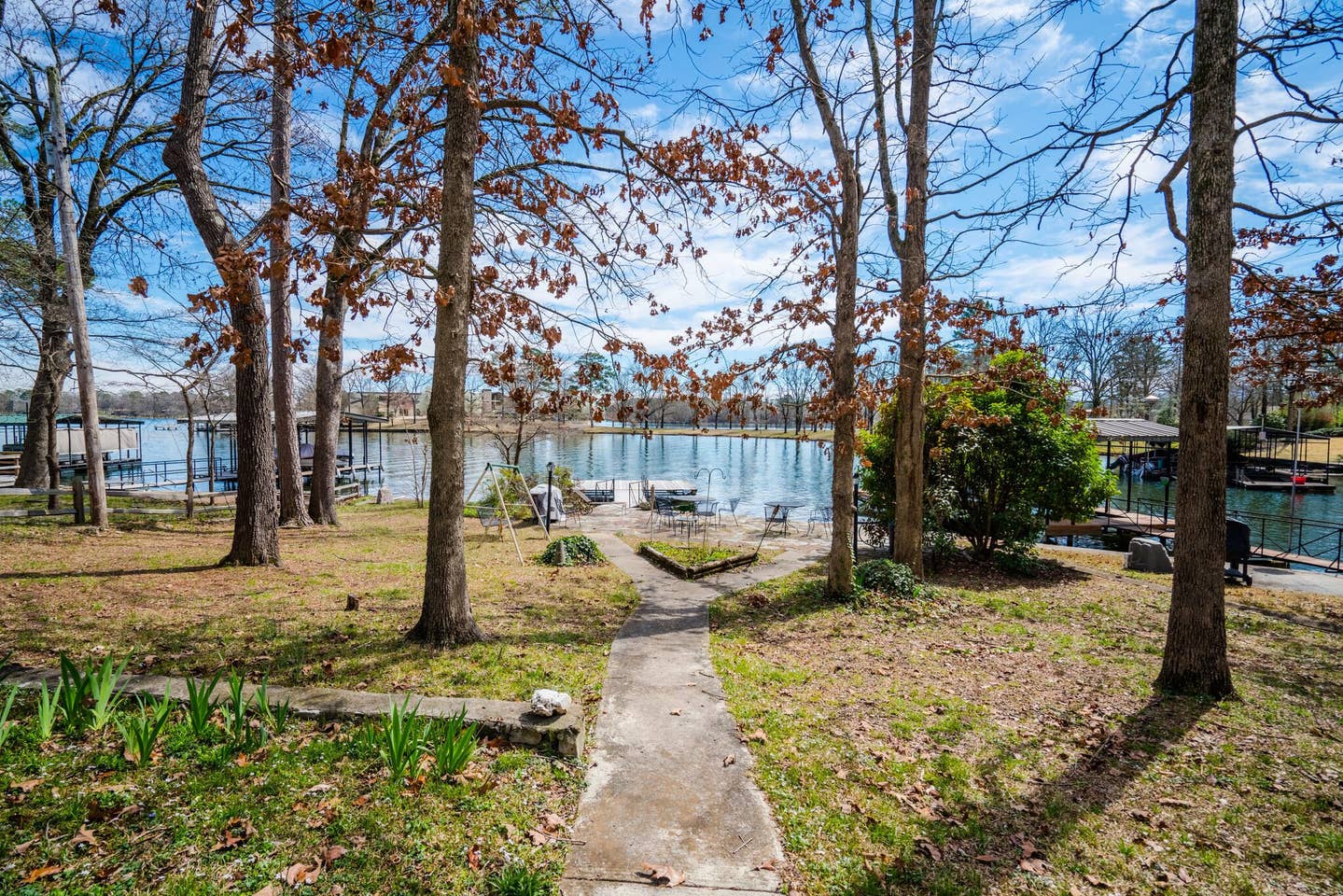 A path leading to a lake surrounded by trees on a sunny day.