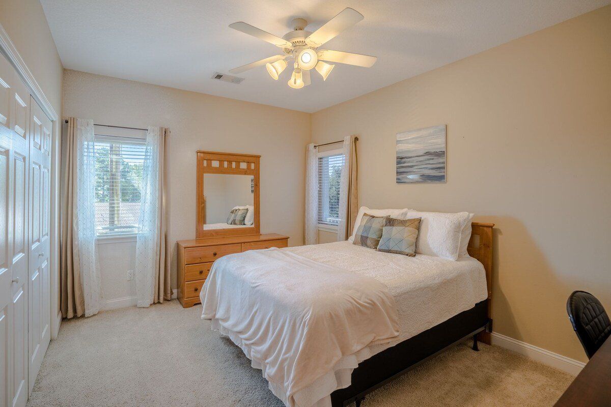 A bedroom with a bed , dresser , mirror and ceiling fan.