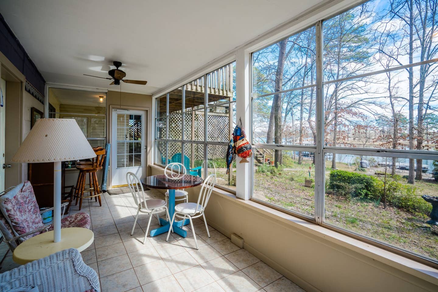 A screened in porch with a table and chairs and a ceiling fan.