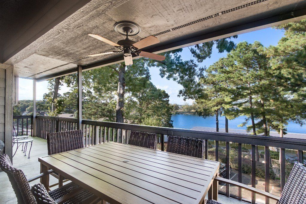 A patio with a table and chairs and a ceiling fan overlooking a lake