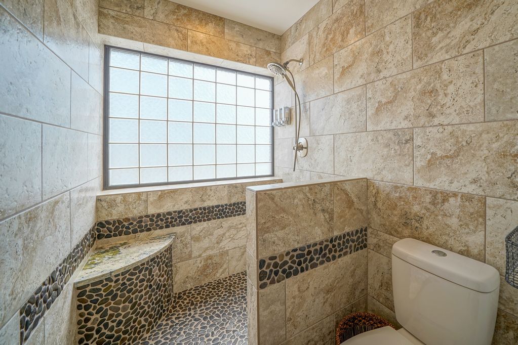 A bathroom with a toilet , shower , and window.